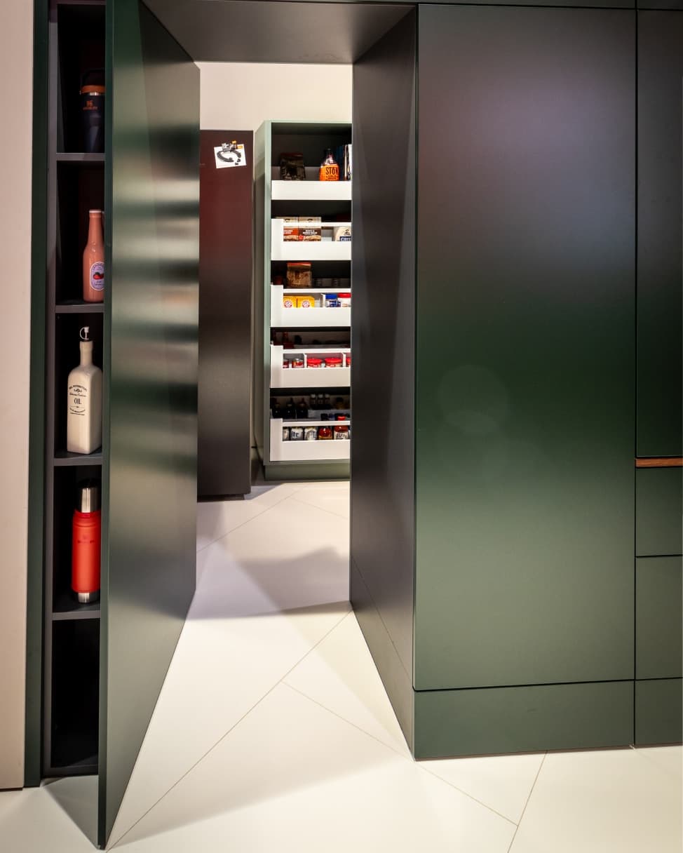 Kuchyň s ostrůvkem s dovnitř otvíranými dvířky, která vytvářejí spíž